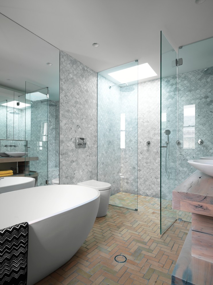 На фото: ванная комната среднего размера в современном стиле с фасадами цвета дерева среднего тона, двойным душем, серыми стенами, кирпичным полом, настольной раковиной, столешницей из дерева, серой плиткой и коричневой столешницей