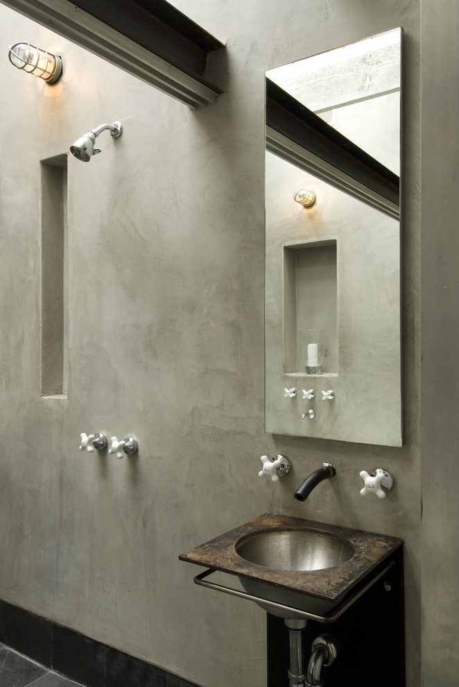 Modelo de cuarto de baño industrial con lavabo suspendido, paredes beige y microcemento