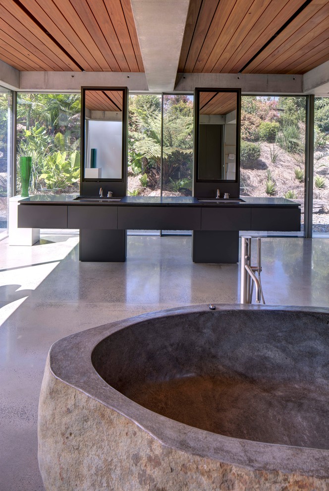 Ispirazione per una grande stanza da bagno padronale design con ante lisce, ante nere, vasca freestanding, pavimento in cemento, pavimento grigio e top nero