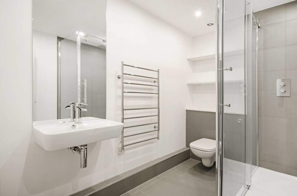 Cette photo montre une petite salle d'eau tendance avec une douche ouverte, WC suspendus, un carrelage gris, des carreaux de porcelaine, un mur blanc, un sol en carrelage de porcelaine et un lavabo suspendu.