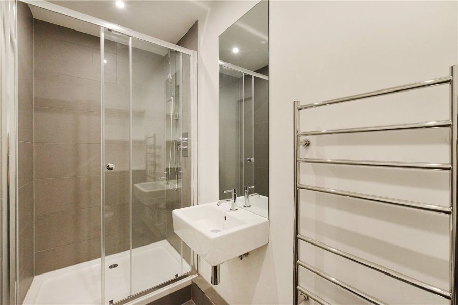 Photo of a small contemporary ensuite bathroom in London with a walk-in shower, a wall mounted toilet, grey tiles, porcelain tiles, white walls, porcelain flooring and a wall-mounted sink.