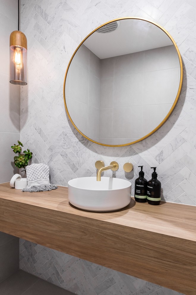 This is an example of a medium sized modern shower room bathroom in Melbourne with open cabinets, medium wood cabinets, a two-piece toilet, white tiles, grey walls, a built-in sink, wooden worktops, grey floors and blue worktops.