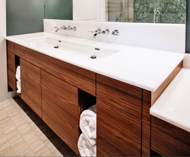 This is an example of a large modern ensuite bathroom in Toronto with flat-panel cabinets, a walk-in shower, a one-piece toilet, white tiles, stone slabs, lino flooring, solid surface worktops, medium wood cabinets, a freestanding bath, grey walls and a built-in sink.