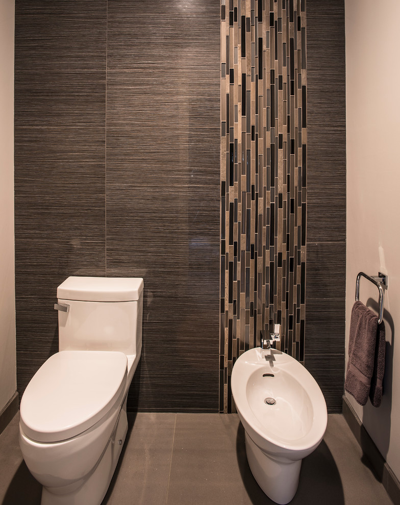 Idée de décoration pour un très grand WC et toilettes design en bois brun avec un placard à porte plane, WC à poser, un carrelage gris, des carreaux de porcelaine, un mur gris, un sol en carrelage de porcelaine, une vasque, un plan de toilette en quartz modifié et un sol gris.