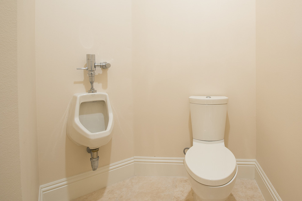 На фото: огромный туалет в средиземноморском стиле с писсуаром, бежевыми стенами и полом из травертина