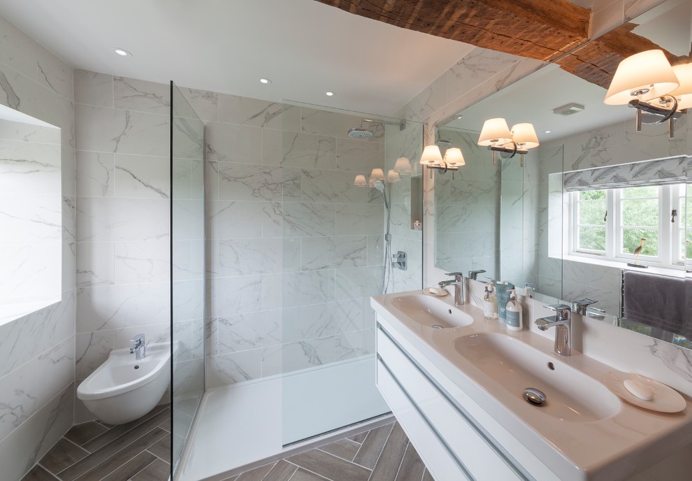 Inredning av ett lantligt mellanstort en-suite badrum, med en öppen dusch, vit kakel, vita väggar, klinkergolv i porslin, ett konsol handfat, grått golv, med dusch som är öppen, släta luckor, vita skåp och en bidé