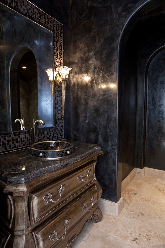 Inredning av ett medelhavsstil mycket stort badrum med dusch, med ett fristående handfat, möbel-liknande, skåp i mörkt trä, marmorbänkskiva, en toalettstol med separat cisternkåpa, svart kakel, stenkakel, svarta väggar och travertin golv