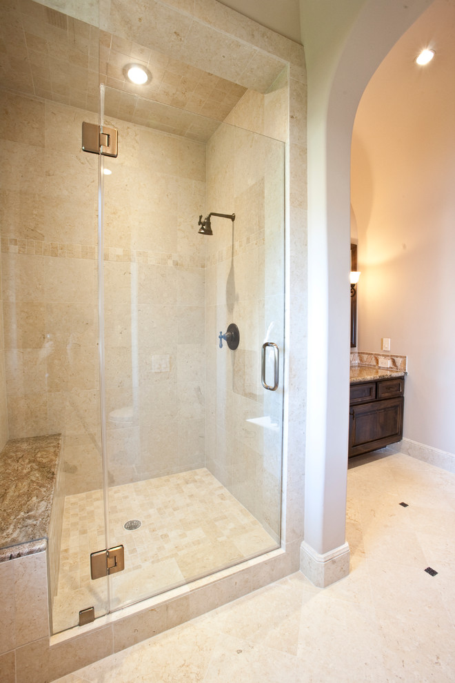 This is an example of an expansive mediterranean shower room bathroom in Houston with a built-in sink, raised-panel cabinets, dark wood cabinets, marble worktops, a built-in bath, an alcove shower, a two-piece toilet, beige tiles, stone tiles, beige walls and travertine flooring.