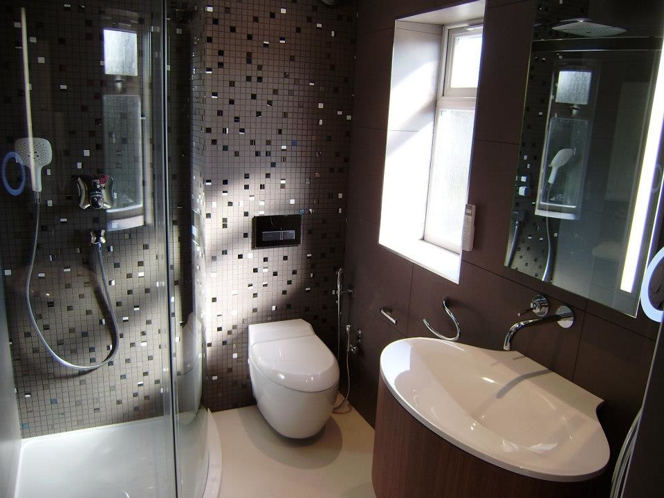 Exemple d'une salle d'eau tendance en bois brun de taille moyenne avec un lavabo suspendu, un placard à porte plane, un plan de toilette en surface solide, une douche double, WC suspendus, un carrelage gris, des carreaux de porcelaine, un mur gris et un sol en carrelage de porcelaine.