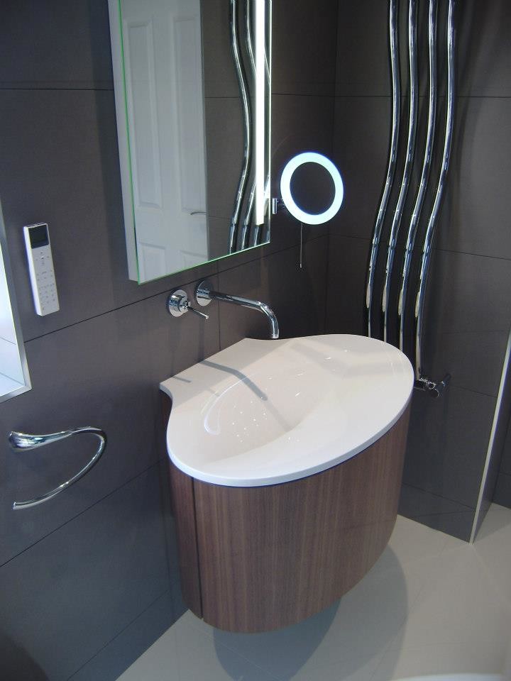 Inspiration for a mid-sized contemporary 3/4 gray tile and porcelain tile porcelain tile double shower remodel in West Midlands with a wall-mount sink, flat-panel cabinets, medium tone wood cabinets, solid surface countertops, a wall-mount toilet and gray walls