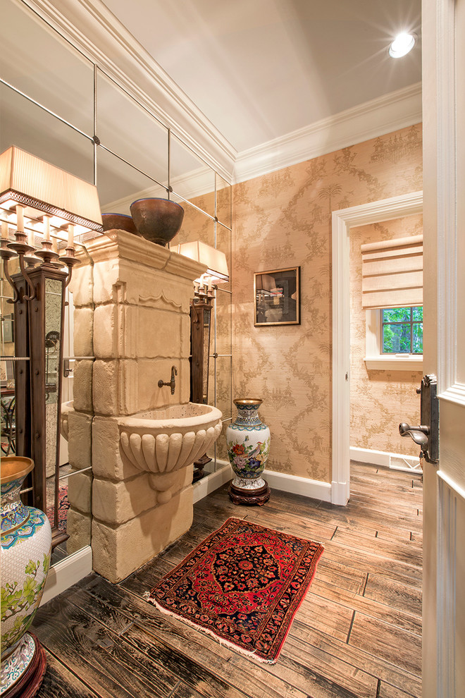 Inredning av ett klassiskt badrum, med ett väggmonterat handfat, spegel istället för kakel, bruna väggar och mörkt trägolv