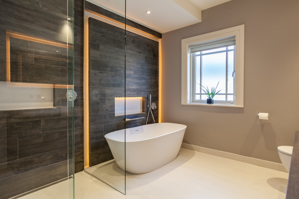 Réalisation d'une salle d'eau design avec une baignoire indépendante, un combiné douche/baignoire, un carrelage noir, un mur gris et un sol blanc.