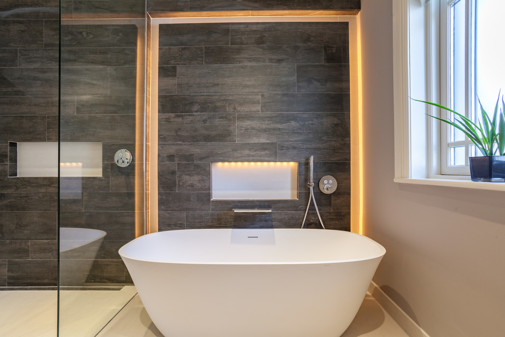Trendy brown tile white floor freestanding bathtub photo in Dublin