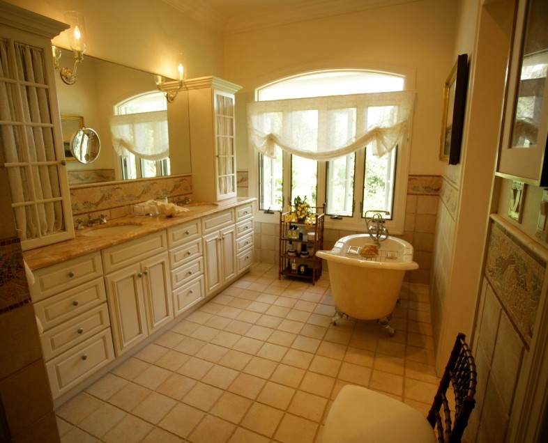 Immagine di una stanza da bagno classica con vasca con piedi a zampa di leone, ante con bugna sagomata, top in marmo, piastrelle beige e piastrelle in pietra