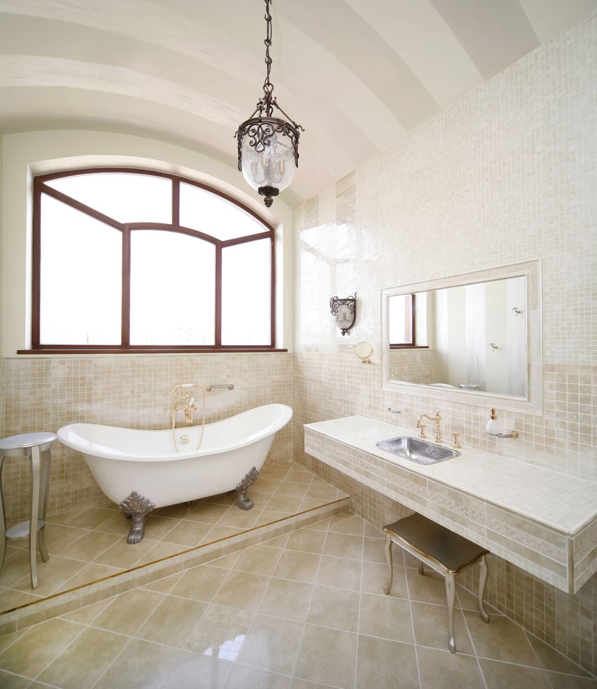 Esempio di una stanza da bagno padronale classica di medie dimensioni con vasca con piedi a zampa di leone, piastrelle beige, piastrelle a mosaico, pareti beige, pavimento con piastrelle in ceramica, lavabo da incasso, top piastrellato, pavimento beige e top beige