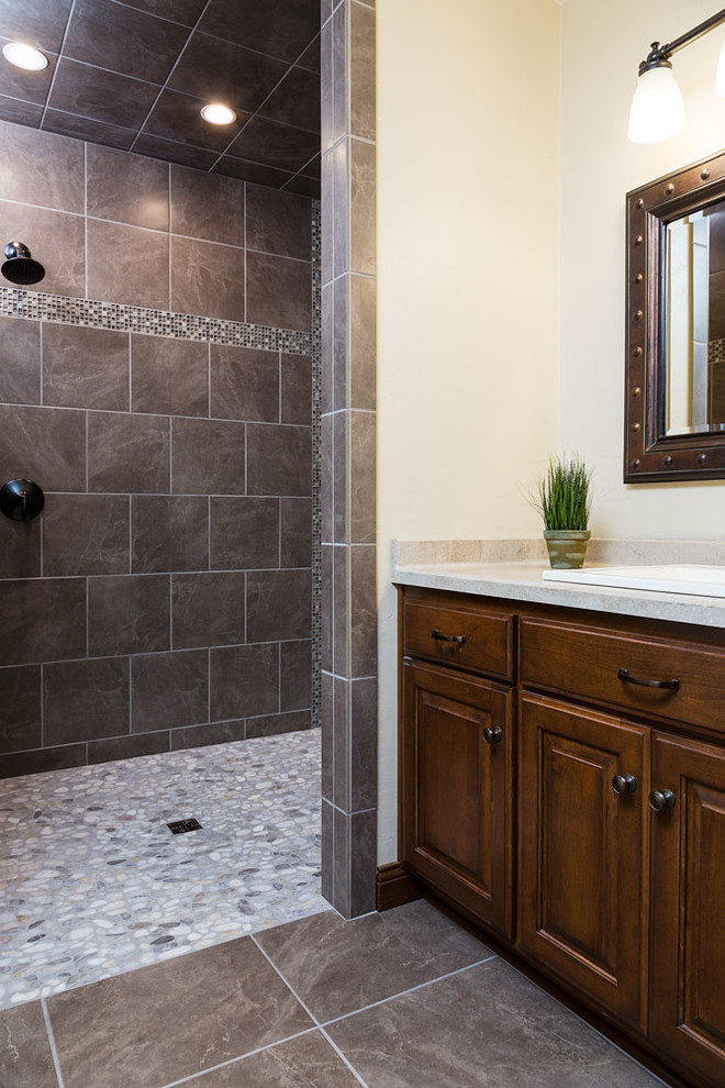 Uriges Badezimmer mit hellbraunen Holzschränken, Duschnische, beiger Wandfarbe, Einbauwaschbecken, grauem Boden und offener Dusche in Sonstige
