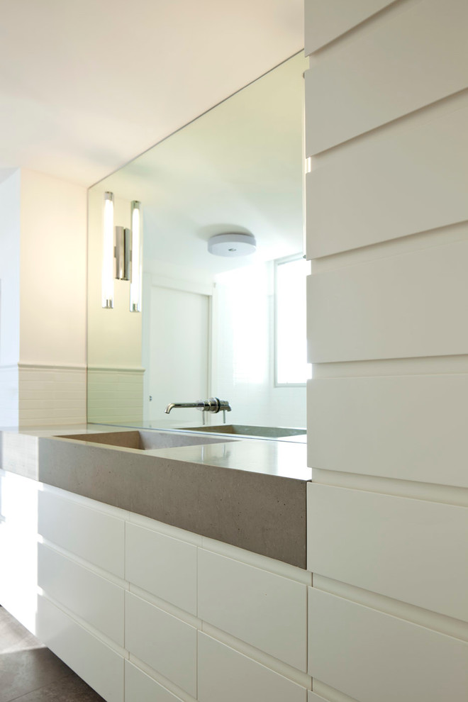 Свежая идея для дизайна: ванная комната среднего размера в современном стиле с монолитной раковиной, плоскими фасадами, белыми фасадами, столешницей из бетона, белой плиткой, керамогранитной плиткой, белыми стенами и полом из известняка - отличное фото интерьера