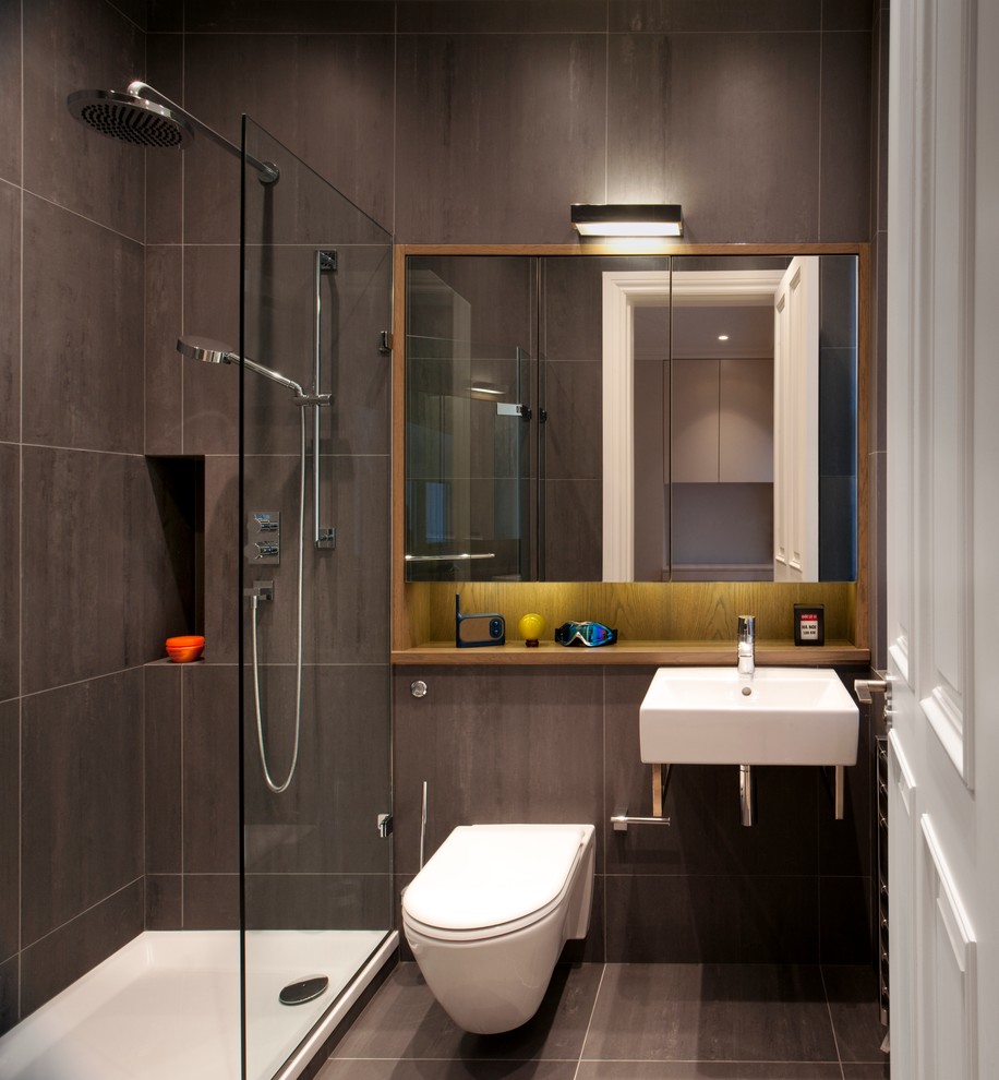 Exemple d'une petite salle d'eau tendance avec un lavabo suspendu, une douche d'angle, WC suspendus, un carrelage marron, un carrelage de pierre et un mur gris.