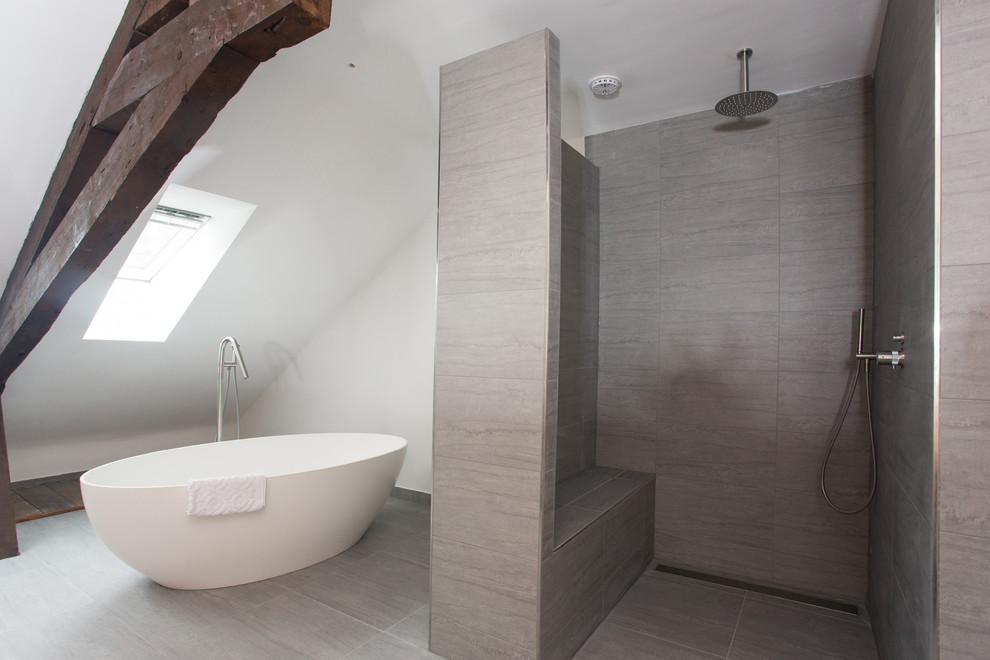 Ispirazione per una grande stanza da bagno padronale moderna con ante in legno scuro, top in superficie solida, vasca freestanding e piastrelle grigie