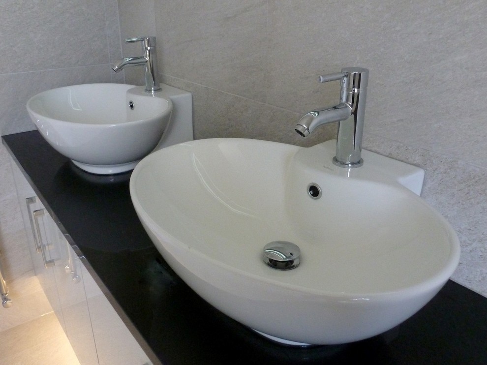 Inredning av ett modernt stort en-suite badrum, med ett konsol handfat, möbel-liknande, vita skåp, granitbänkskiva, ett fristående badkar, en öppen dusch, en toalettstol med hel cisternkåpa, grå kakel, porslinskakel, grå väggar och klinkergolv i porslin