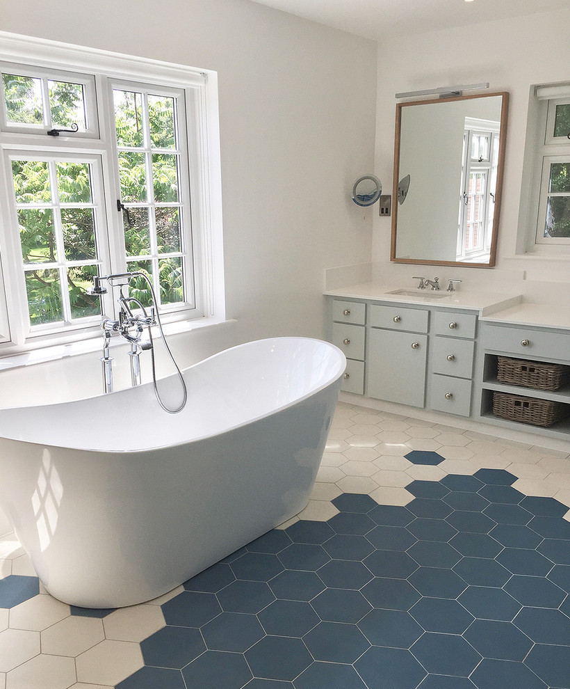 Bild på ett stort funkis badrum, med ett fristående badkar, blå kakel, cementkakel, ett konsol handfat och bänkskiva i kvartsit