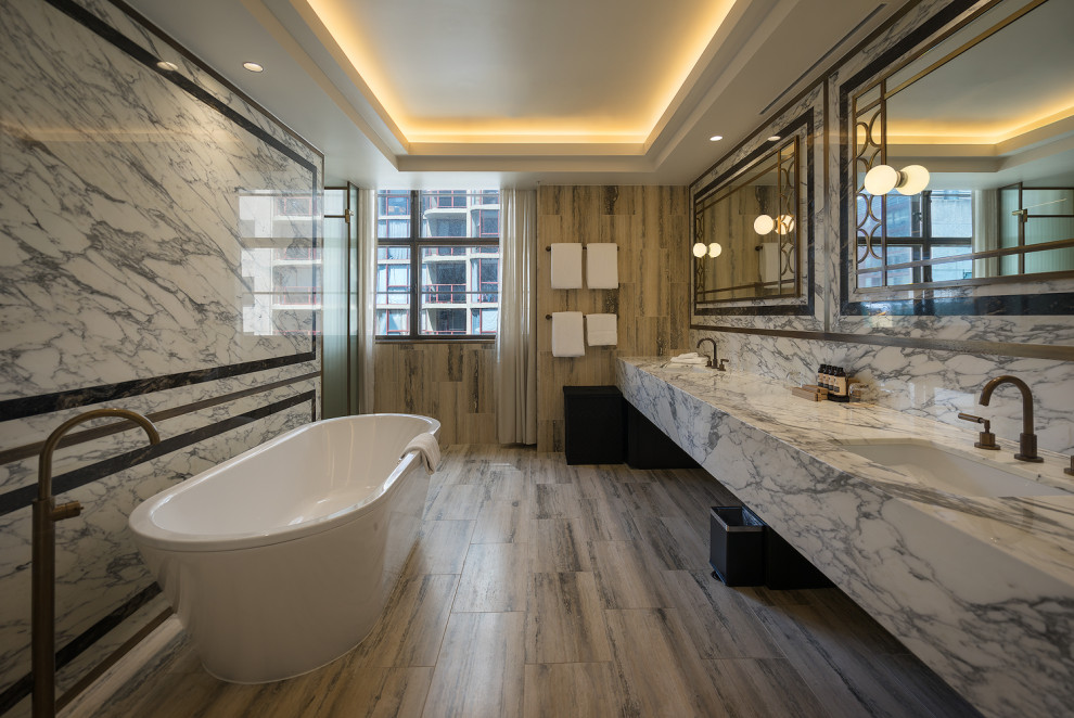 На фото: большая ванная комната в современном стиле с открытым душем, серой плиткой, серыми стенами, полом из цементной плитки, монолитной раковиной, мраморной столешницей, серым полом, белой столешницей, тумбой под две раковины и деревянным потолком
