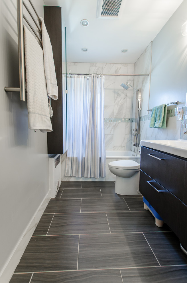 Design ideas for a medium sized traditional ensuite bathroom in New York with flat-panel cabinets, black cabinets, an alcove bath, a shower/bath combination, a one-piece toilet, blue tiles, grey tiles, white tiles, mosaic tiles, blue walls, laminate floors, an integrated sink, grey floors and a shower curtain.