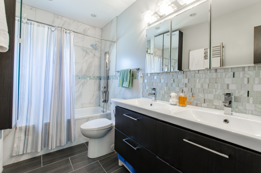 Foto på ett mellanstort vintage en-suite badrum, med släta luckor, svarta skåp, ett badkar i en alkov, en dusch/badkar-kombination, en toalettstol med hel cisternkåpa, blå kakel, grå kakel, vit kakel, mosaik, blå väggar, laminatgolv, ett integrerad handfat, grått golv och dusch med duschdraperi