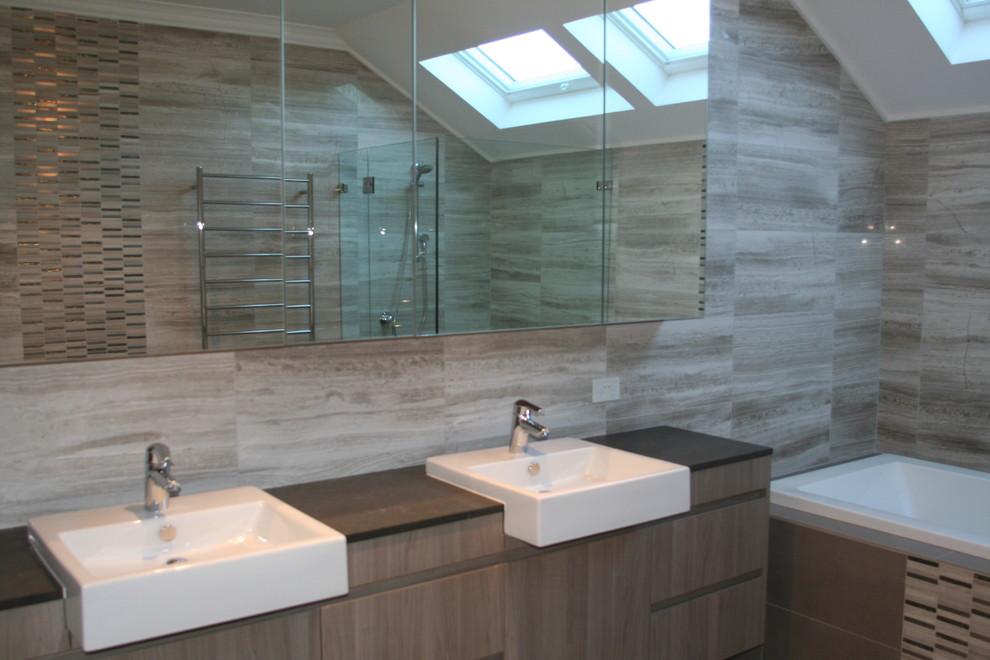 This is an example of a contemporary bathroom in Sydney with a vessel sink, a built-in bath, grey tiles and glass tiles.