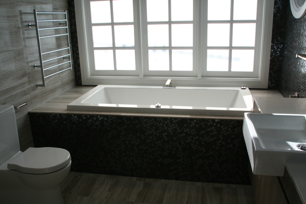 На фото: ванная комната в современном стиле с серой плиткой, столешницей из искусственного кварца, накладной ванной и унитазом-моноблоком