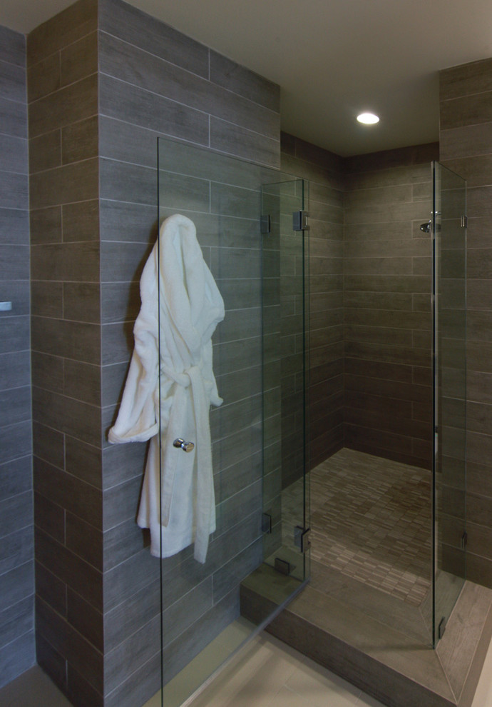 Cette image montre une salle de bain design en bois brun avec un lavabo encastré, un placard en trompe-l'oeil, un plan de toilette en calcaire, une douche d'angle, WC suspendus, un carrelage gris et des carreaux de céramique.
