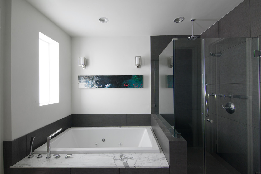 На фото: ванная комната в современном стиле с врезной раковиной, мраморной столешницей, накладной ванной, двойным душем и серой плиткой с