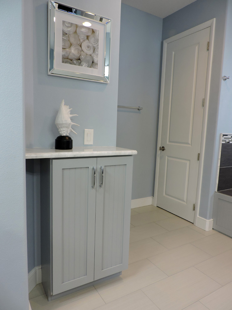 Imagen de cuarto de baño actual con armarios estilo shaker, puertas de armario azules, baldosas y/o azulejos beige y suelo de baldosas de porcelana