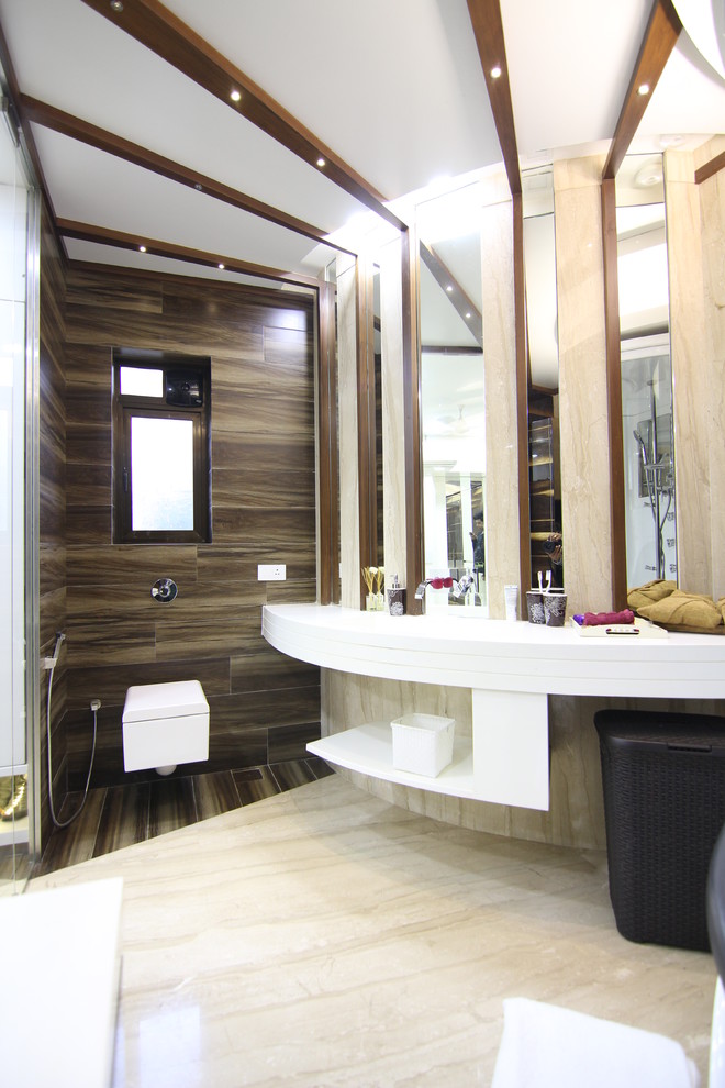 Large trendy brown tile and ceramic tile marble floor tub/shower combo photo in Mumbai with solid surface countertops, a wall-mount toilet and beige walls