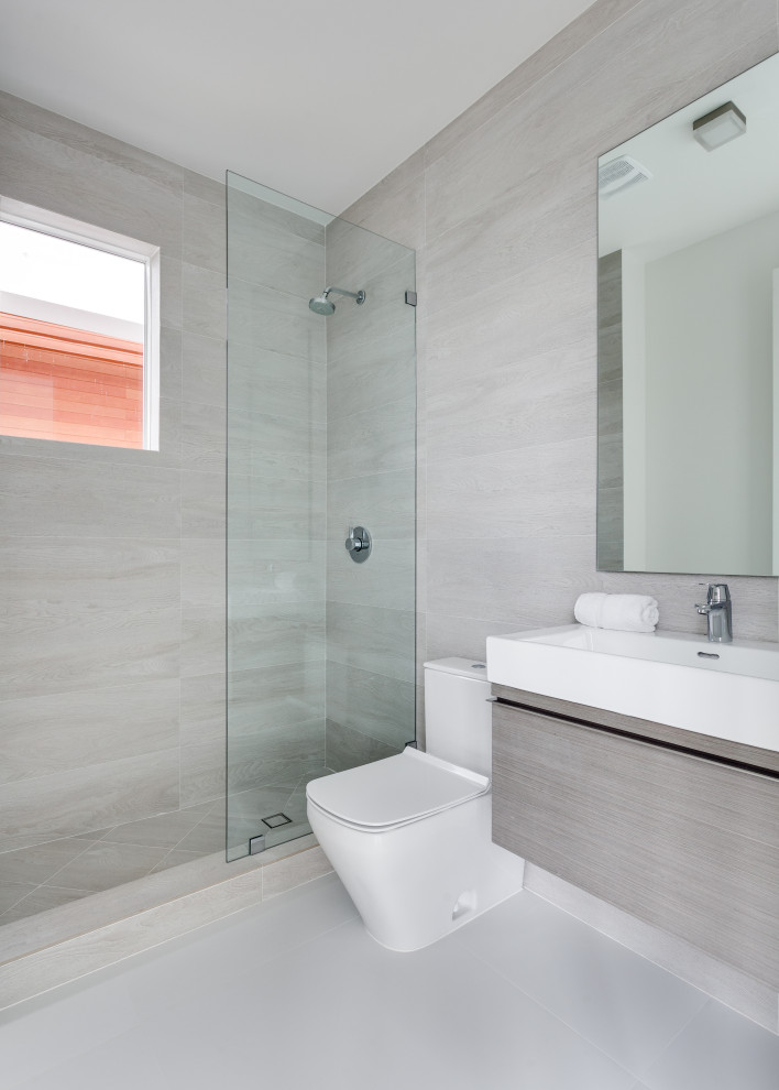 Modernes Badezimmer mit flächenbündigen Schrankfronten, grauen Schränken, Duschnische, Toilette mit Aufsatzspülkasten, grauen Fliesen, Waschtischkonsole, grauem Boden, Einzelwaschbecken und schwebendem Waschtisch in Miami