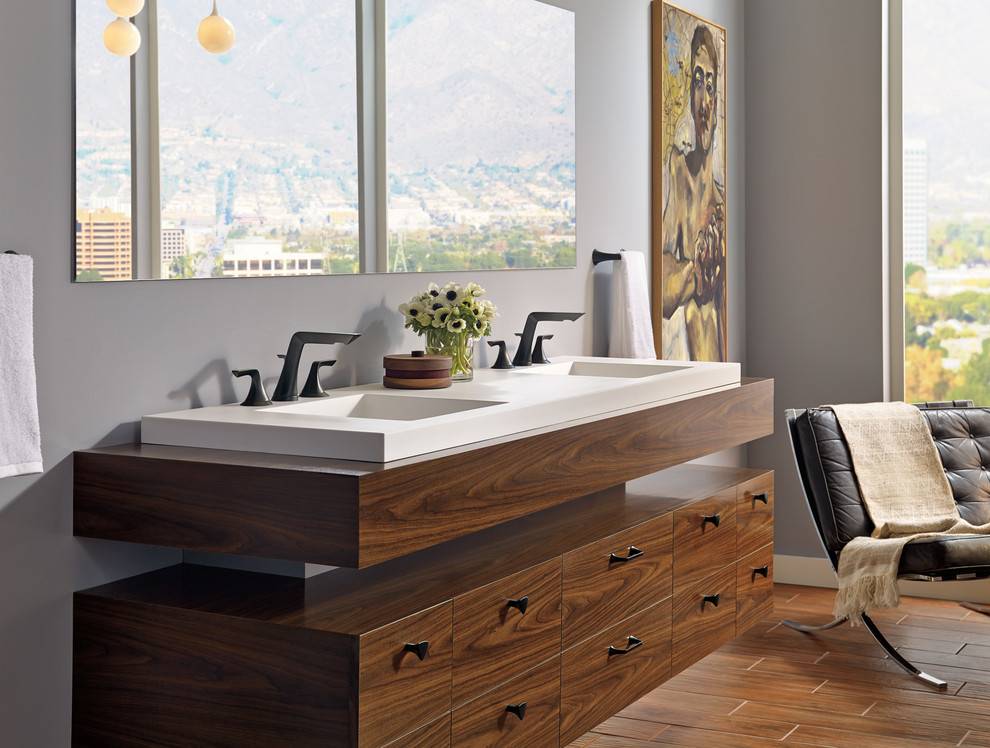 Esempio di una stanza da bagno padronale minimal con consolle stile comò, ante in legno bruno, pareti grigie, pavimento in legno massello medio, lavabo integrato, top in superficie solida e pavimento marrone