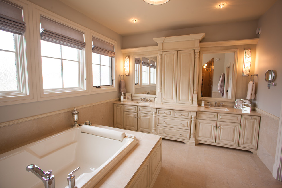 Mid-sized elegant master beige tile and ceramic tile ceramic tile drop-in bathtub photo in Calgary with an undermount sink, raised-panel cabinets, distressed cabinets, quartzite countertops and beige walls