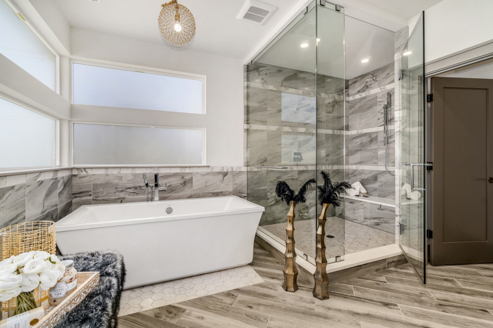 Inspiration for a contemporary bathroom in Seattle with a freestanding bath, grey tiles, white walls, grey floors and a shower bench.