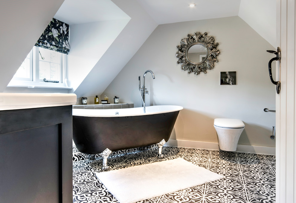 This is an example of an ensuite bathroom in Surrey with shaker cabinets, black cabinets, a claw-foot bath, a wall mounted toilet, grey walls, mosaic tile flooring and black floors.