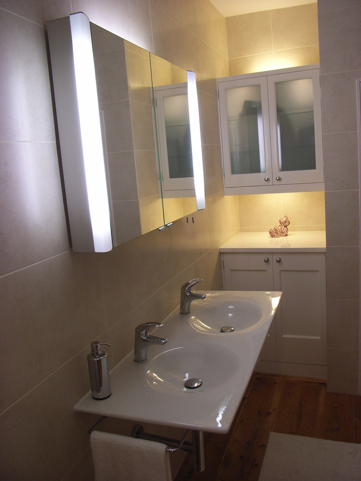 Inspiration för ett mellanstort funkis en-suite badrum, med ett väggmonterat handfat, luckor med glaspanel, vita skåp, träbänkskiva, beige kakel, porslinskakel och ljust trägolv