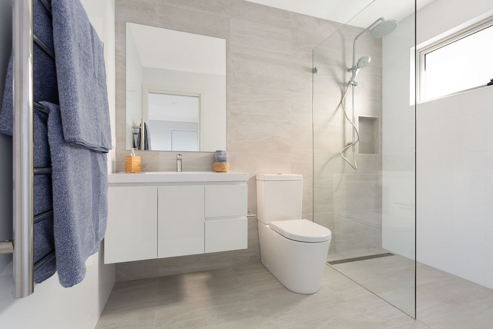 Modernes Duschbad mit flächenbündigen Schrankfronten, weißen Schränken, offener Dusche, Toilette mit Aufsatzspülkasten, beigen Fliesen, beigem Boden, offener Dusche und weißer Waschtischplatte in Sydney