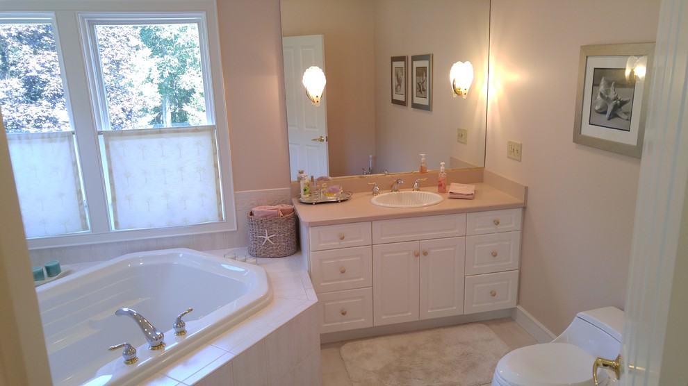 Inredning av ett modernt stort en-suite badrum, med ett nedsänkt handfat, släta luckor, vita skåp, bänkskiva i kvarts, ett hörnbadkar, en hörndusch, en bidé, beige kakel, keramikplattor, rosa väggar och klinkergolv i porslin