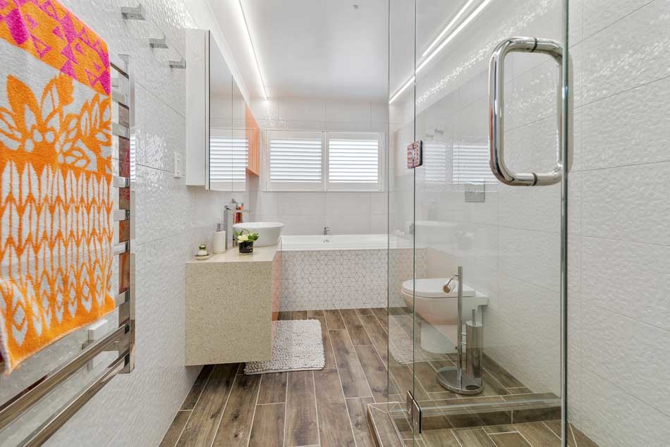 Trendy kids' white tile and ceramic tile porcelain tile drop-in bathtub photo in Hamilton with furniture-like cabinets, orange cabinets, a wall-mount toilet, white walls, a vessel sink and quartz countertops