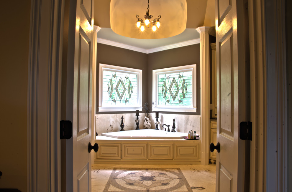 Klassisk inredning av ett stort en-suite badrum, med ett undermonterad handfat, luckor med upphöjd panel, granitbänkskiva, ett hörnbadkar, en dubbeldusch, beige kakel, stenkakel, bruna väggar, travertin golv, beige skåp och en toalettstol med separat cisternkåpa