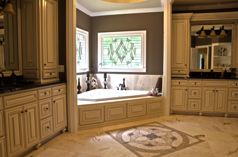 Example of a large classic master beige tile and stone tile travertine floor bathroom design in Atlanta with an undermount sink, raised-panel cabinets, beige cabinets, granite countertops, brown walls and a two-piece toilet