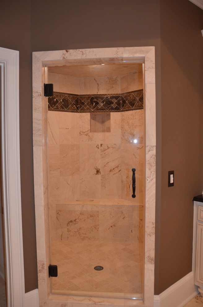 Photo of a large classic ensuite bathroom in Atlanta with a submerged sink, raised-panel cabinets, beige cabinets, granite worktops, a corner bath, a double shower, a two-piece toilet, beige tiles, stone tiles, brown walls and travertine flooring.