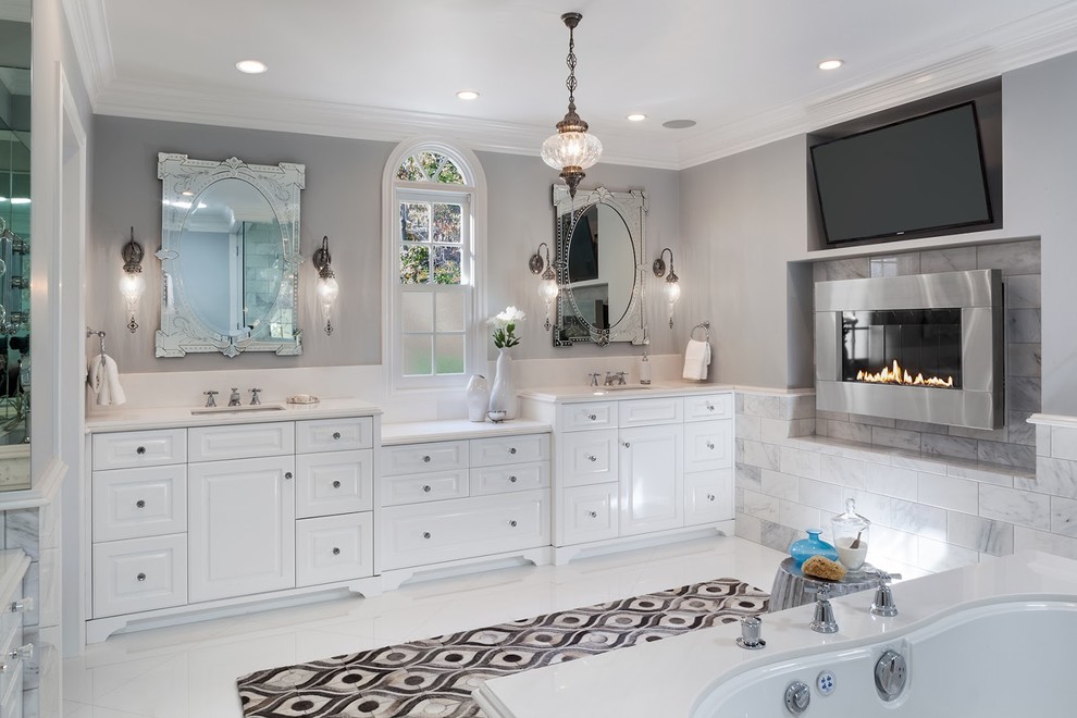 Example of a large trendy master white tile and marble tile porcelain tile and white floor corner bathtub design in Los Angeles with raised-panel cabinets, white cabinets, gray walls, an undermount sink and quartz countertops