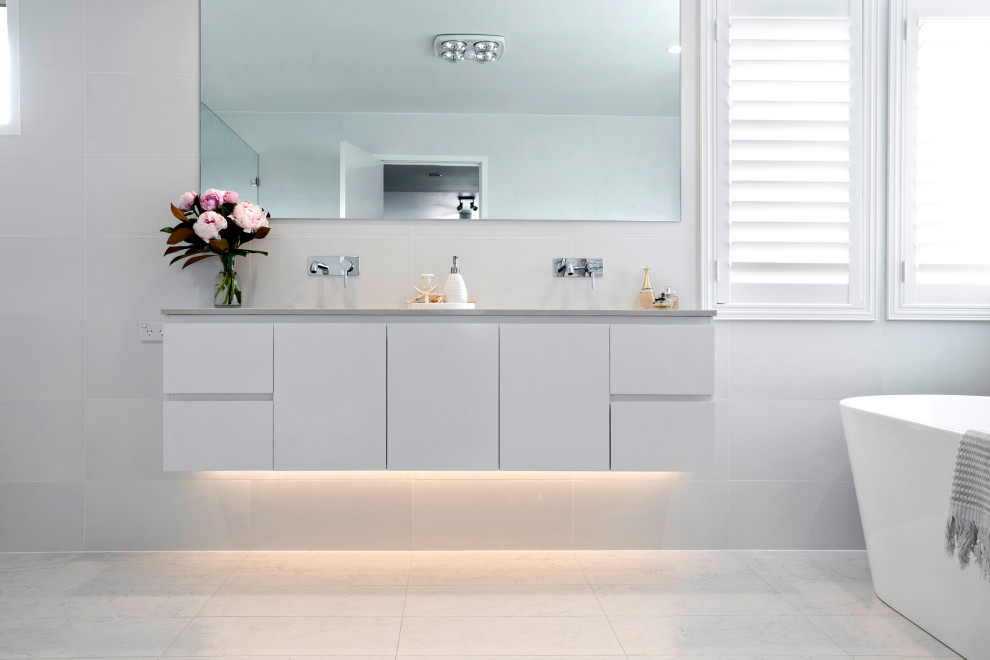 На фото: большая ванная комната в стиле модернизм с отдельно стоящей ванной, открытым душем, инсталляцией, белой плиткой, керамогранитной плиткой и открытым душем с