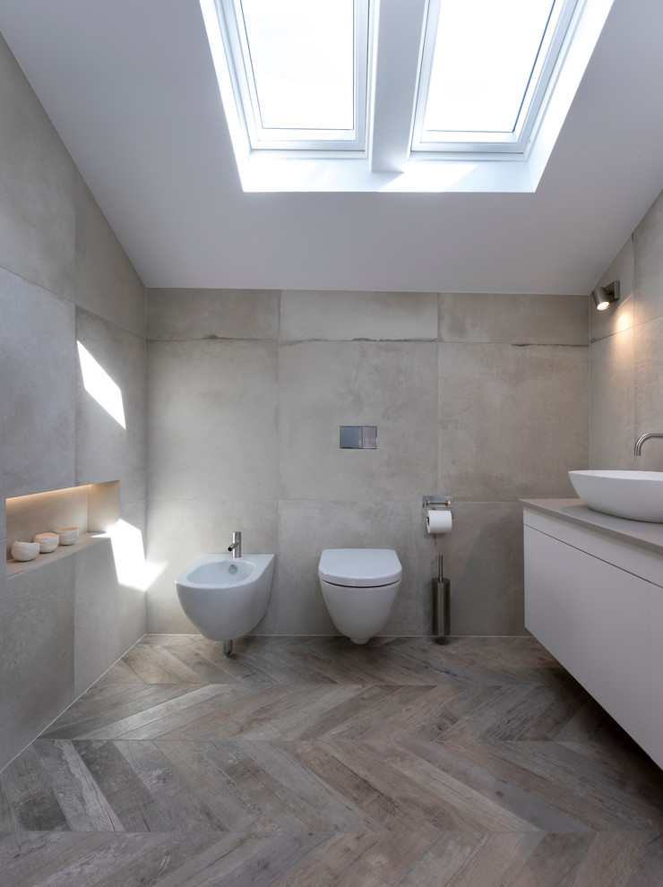 Example of a mid-sized trendy master gray tile and ceramic tile ceramic tile and gray floor bathroom design in Cheshire with furniture-like cabinets, white cabinets, a wall-mount toilet, white walls, a wall-mount sink and quartzite countertops