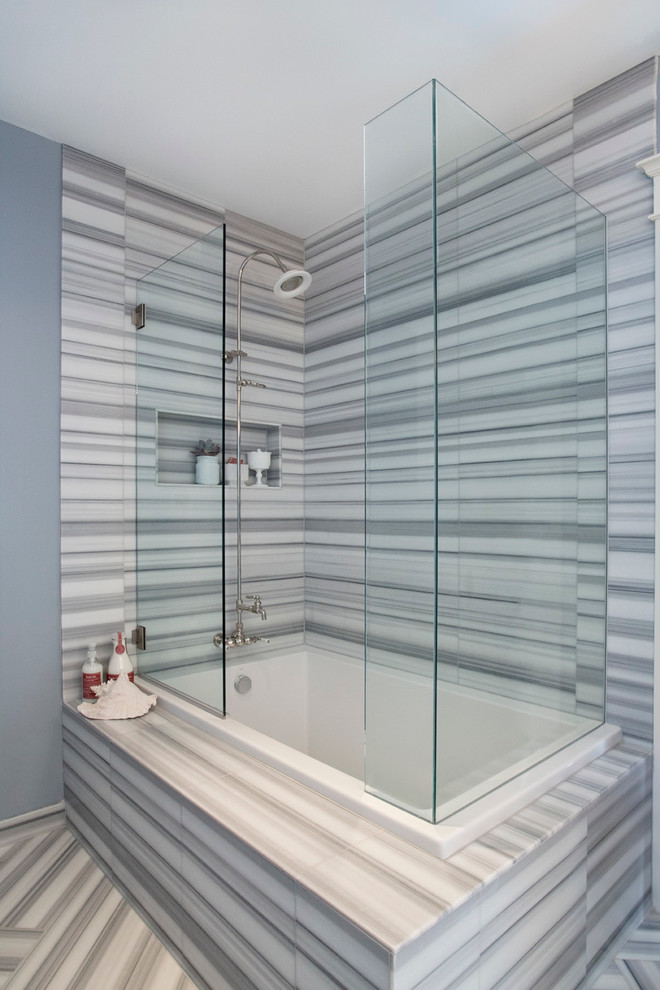 Exemple d'une salle de bain grise et blanche tendance avec un combiné douche/baignoire, un carrelage gris, des dalles de pierre et une baignoire posée.